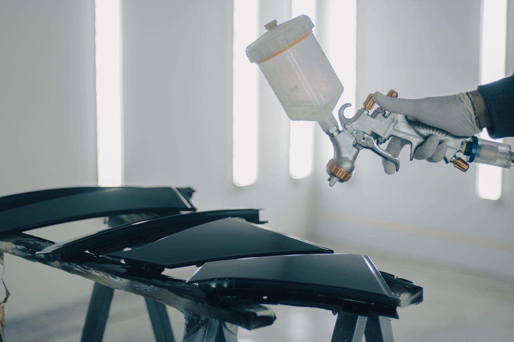 Spray gun applying paint in a body shop